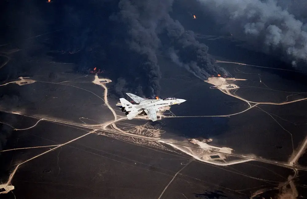 A U.S. Navy F-14A flies over burning Kuwaiti oil wells in 1991, after the Gulf War.